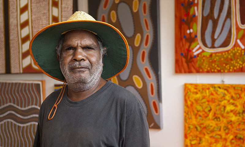 Aboriginal middle aged man in front of Indigenous Art
